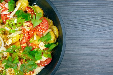 Ahşap bir masada siyah bir tavada otlu, baharatlı ve sebzeli kızarmış patates pişirdim. Boşluğu kopyala