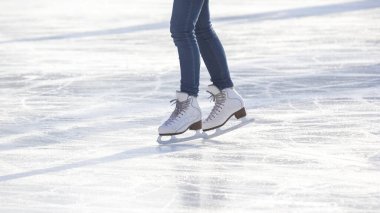 Mavi kotlu ve buz pistinde beyaz patenli bir kadının bacakları. Hobiler ve boş vakitler. kış sporları