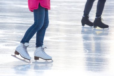 Mavi kotlu ve buz pistinde beyaz patenli bir kadının bacakları. Hobiler ve boş vakitler. kış sporları