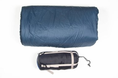 Beyaz arka planda katlanmış uyku tulumu. Turizm ve kamp malzemeleri