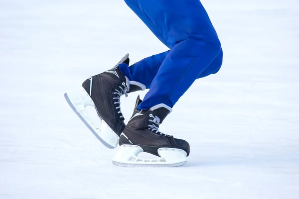 Legs of a man skating on an ice rink. Hobbies and sports. Vacations and winter activities