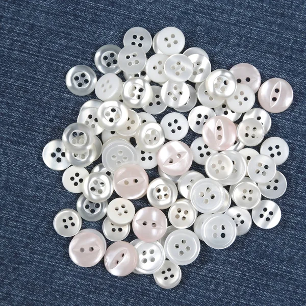 Plastic shiny buttons for clothes on a fabric background. Fashion and clothing. Factory industry