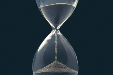Karanlık bir arka planda kum saati. Vakit nakittir. İş çözümleri zamanında.