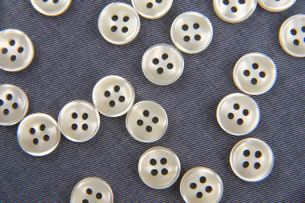 Plastic shiny buttons for clothes on a fabric background. Fashion and clothing. Factory industry