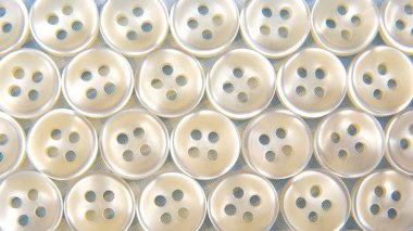 Kumaş arka plandaki kıyafetler için plastik parlak düğmeler. Moda ve giysi. Fabrika endüstrisi