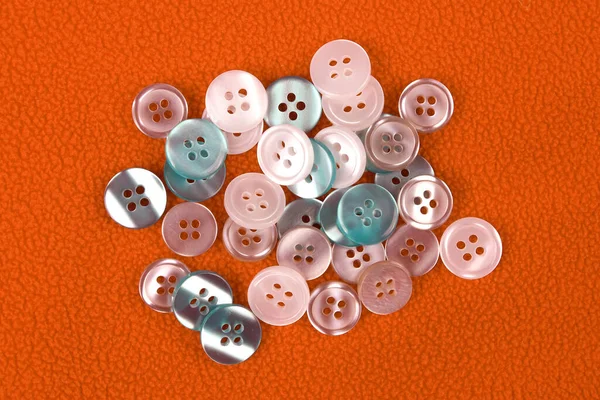 Plastic shiny buttons for clothes on a fabric background. Fashion and clothing. Factory industry