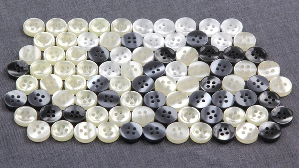 Plastic shiny buttons for clothes on a fabric background. Fashion and clothing. Factory industry