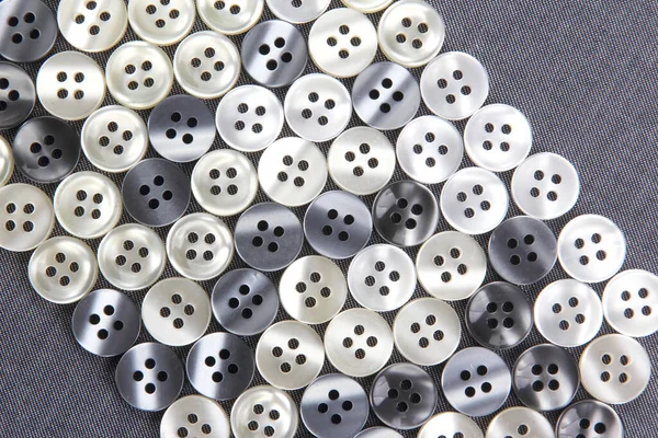 Plastic shiny buttons for clothes on a fabric background. Fashion and clothing. Factory industry