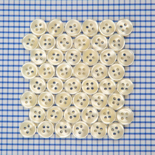 Plastic shiny buttons for clothes on a fabric background. Fashion and clothing. Factory industry