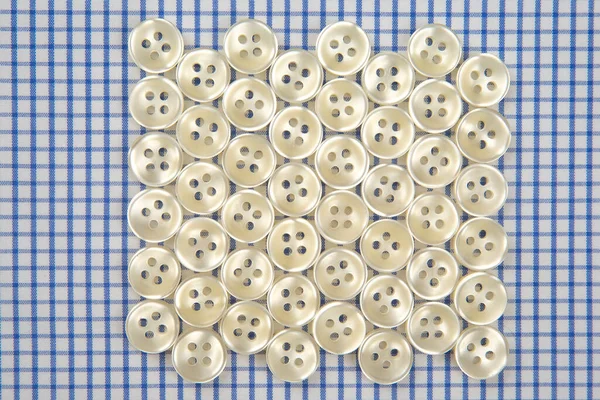 Plastic shiny buttons for clothes on a fabric background. Fashion and clothing. Factory industry