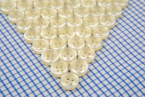 Plastic shiny buttons for clothes on a fabric background. Fashion and clothing. Factory industry