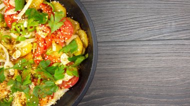 Ahşap bir masada siyah bir tavada otlu, baharatlı ve sebzeli kızarmış patates pişirdim. Boşluğu kopyala