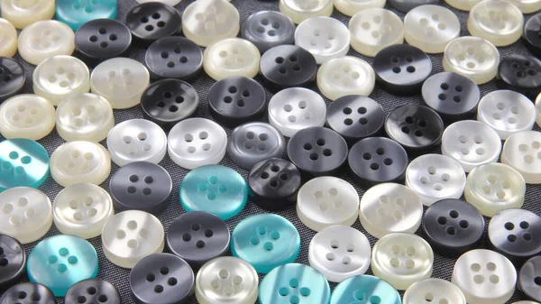 Plastic shiny buttons for clothes on a fabric background. Fashion and clothing. Factory industry