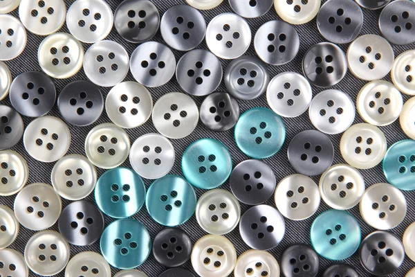 Plastic shiny buttons for clothes on a fabric background. Fashion and clothing. Factory industry