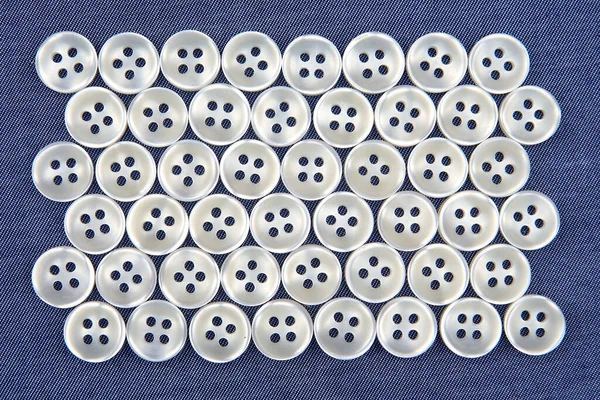 Plastic shiny buttons for clothes on a fabric background. Fashion and clothing. Factory industry