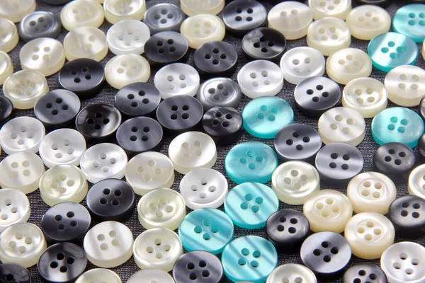 Plastic shiny buttons for clothes on a fabric background. Fashion and clothing. Factory industry