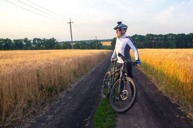 Bisikletli bir bisikletli gün batımını izliyor. Spor ve hobiler. açık hava aktiviteleri
