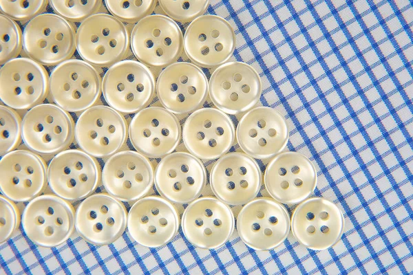 Plastic shiny buttons for clothes on a fabric background. Fashion and clothing. Factory industry