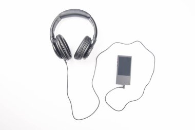 Beyaz arkaplanda dijital ses oynatıcısı olan müzik dinlemek için kulaklıklar