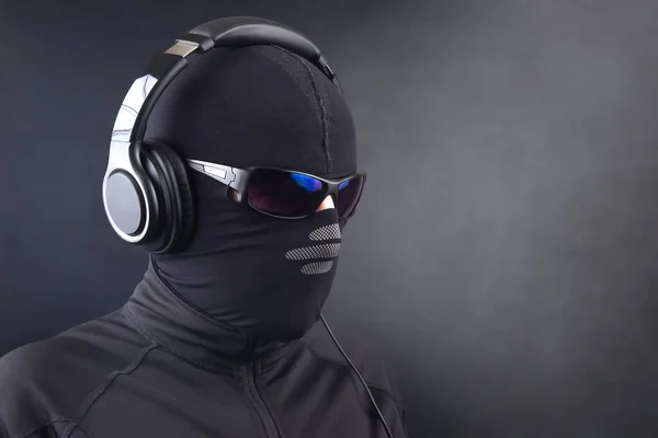 portrait of a man in a black mask and sunglasses listening to music on headphones