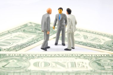 Minyatür insanlar. İş adamı dolar parasına yakın duruyor. İş için yatırımlar ve kazançlar
