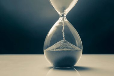 Karanlık bir arka planda kum saati. Vakit nakittir. İş çözümleri zamanında.