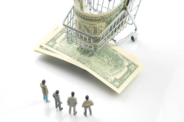 miniature people. businessmen stand near a grocery basket with dollars. business of consumer goods. industrial industry concept