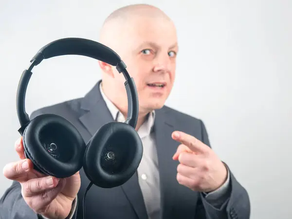 ビジネスマンは音楽を聴くためのヘッドフォンを広告しています — ストック写真