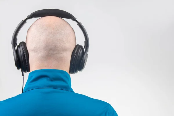 part of the back of the head of a man with headphones in relaxation listening to music on a light background. copy space