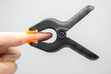 black plastic clothespin hanging on your finger