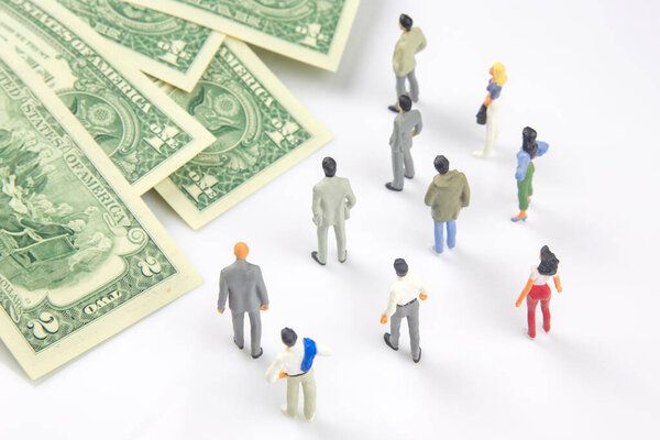 miniature people. different people are standing near dollar money. investments and earnings for work
