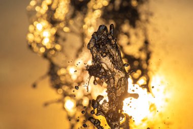 Batan güneşin altındaki çeşmenin damlaları.