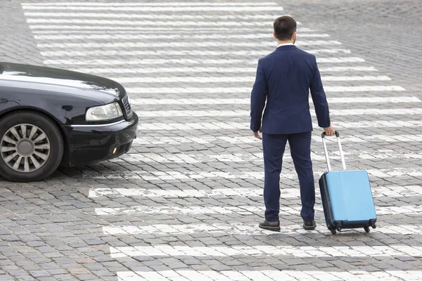 stock image businessman with a travel suitcase walks on a city street crossin