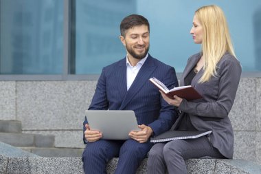 Ellerindeki belge ve dizüstü bilgisayarlarla başarılı iş adamları ve kadınlar iş projelerini tartışıyor