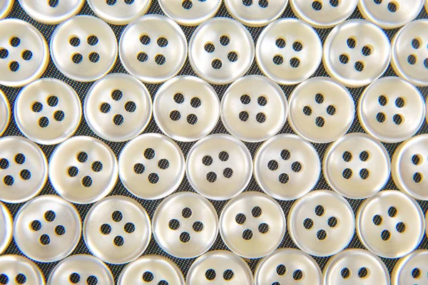 Plastic shiny buttons for clothes on a fabric background. Fashion and clothing. Factory industry