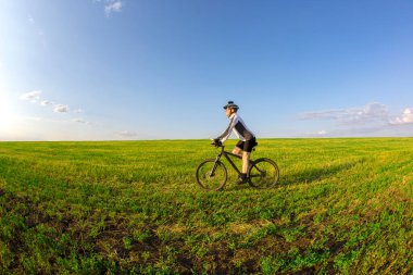 Bisikletçi sahadaki yeşil çimlerin üzerinde bisiklet sürüyor. Açık hava sporları. Sağlıklı yaşam tarzı.