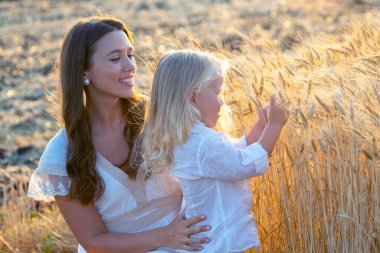 Güzel, uzun saçlı oğluyla buğday tarlasında mutlu bir kadın. Sevgi ve annelik