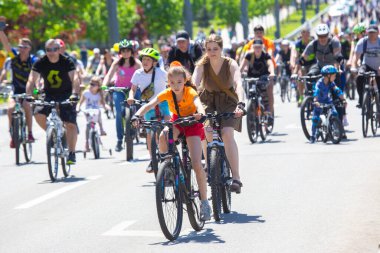 KHARKIV, UKRAINE - 23 Mayıs 2021: Farklı yaşlarda insanlar bir sütunla bisiklet sürerler şehir caddesi boyunca