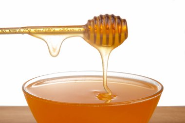 Beyaz arka planda şeffaf bir plakaya damlayan taze bal. organik vitamin sağlıklı gıdalar