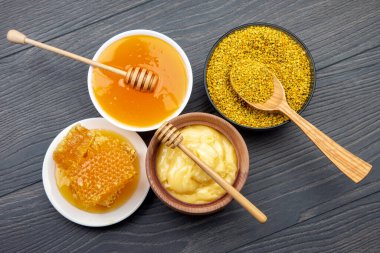 Farklı çeşitlerde taze çiçek balı, polen ve ahşap arka planda kaşıkları olan bal peteği. Organik Vitamin Sağlıklı Gıda