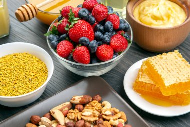 Tahta arka planda taze bal, fındık, çilek ve yaban mersini. sağlıklı organik vitamin yiyeceği.