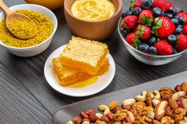 Tahta arka planda taze bal, fındık, çilek ve yaban mersini. sağlıklı organik vitamin yiyeceği.