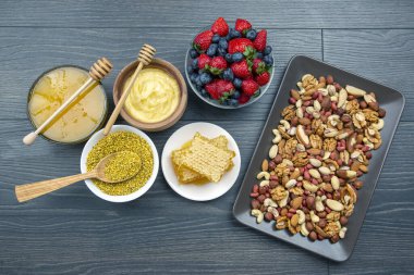 Tahta arka planda taze bal, fındık, çilek ve yaban mersini. sağlıklı organik vitamin yiyeceği.
