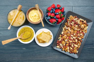 Tahta arka planda taze bal, fındık, çilek ve yaban mersini. sağlıklı organik vitamin yiyeceği.