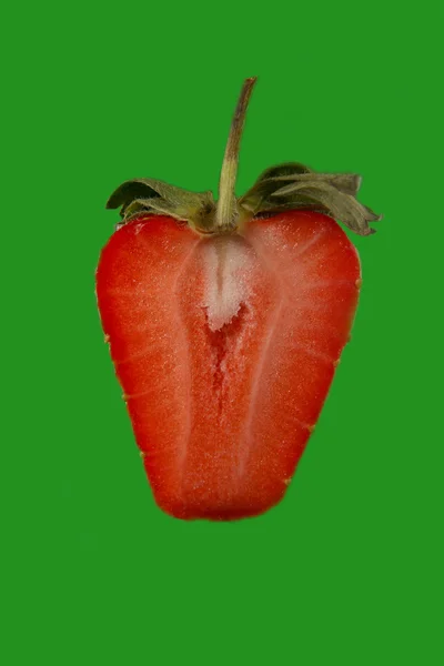 De helft van een aardbei op een helder groene achtergrond — Stockfoto