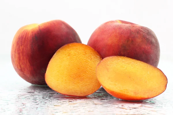 Два спелых персика в капельках воды на белом фоне — стоковое фото