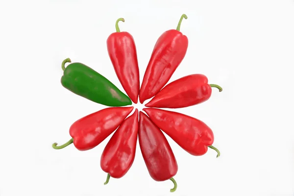 Один зелений і сім червоних солодких перців на білому тлі — стокове фото