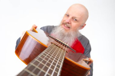 Yaşlı kel adam, gri sakallı, akustik gitarlı, gri spor gömlekli, beyaz arka planda soyutlanmış, tutkulu bir müzik ifadesini vurgulayan biri..