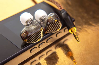 Siyah bir müzik çaların üzerine örülmüş kabloyla altın yansıtıcı bir yüzeye karşı zarif kablo kulaklıklar. Teknoloji, ses ve modern tasarım stok görüntülemesi için uygundur.