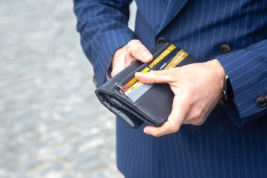 Takım elbiseli iş adamı deri cüzdanını yakına açıyor. Ekonomide finans ve refah